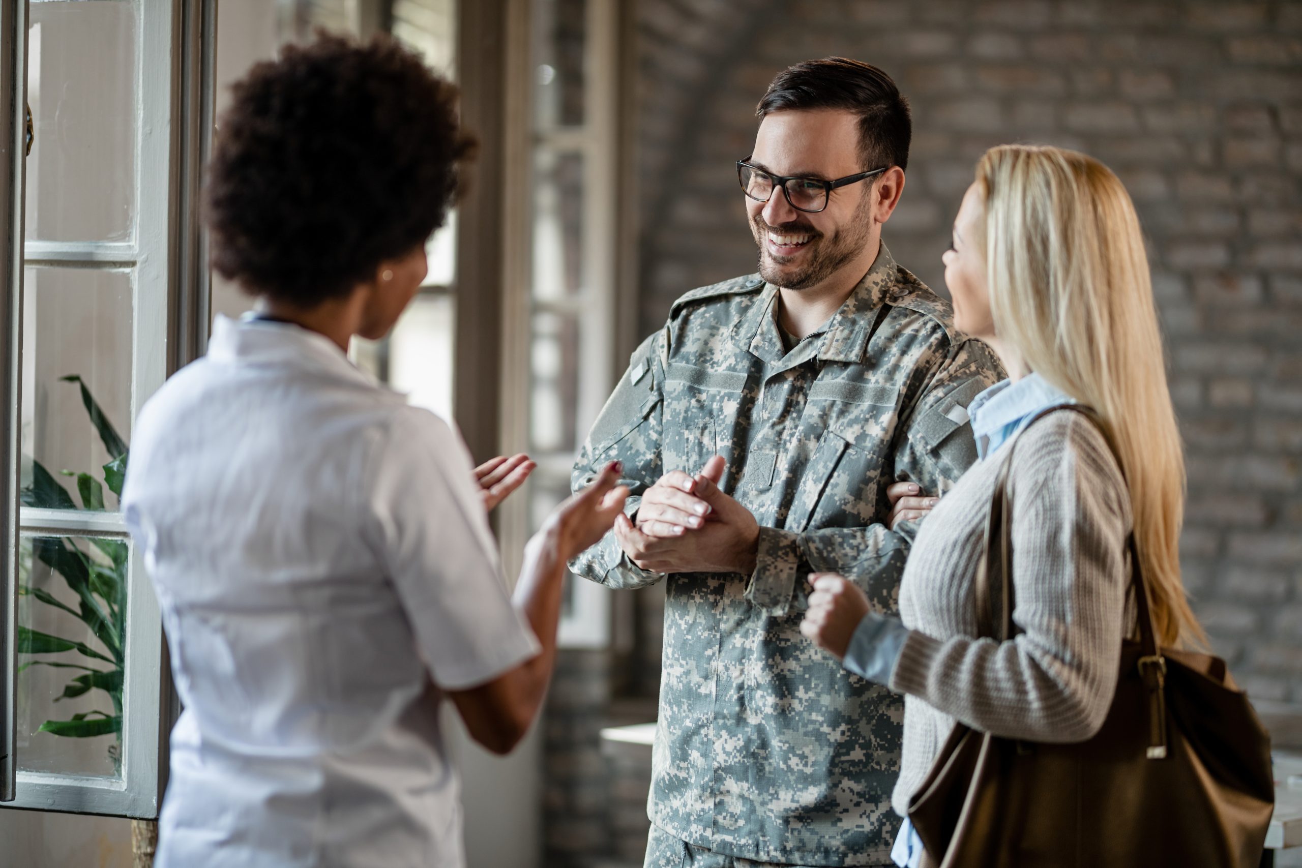 Happy military man and his wife talking to a woman