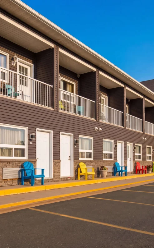 Charming inn exterior with colourful chairs, bright sky, and welcoming atmosphere.