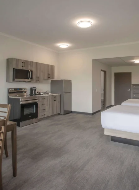 Spacious hotel suite with kitchen, dining table, and two cosy beds.