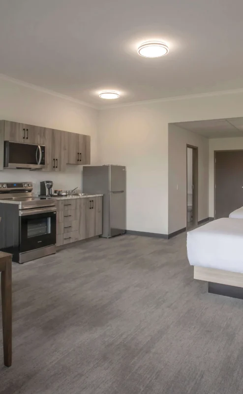 Spacious hotel suite with kitchen, dining table, and two cosy beds.