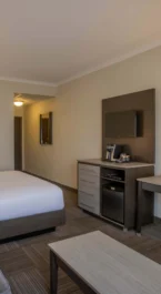 Modern hotel room with double bed, sofa, and workspace.
