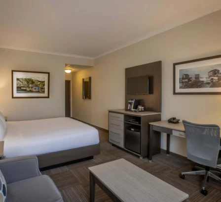Modern hotel room with double bed, sofa, and workspace.