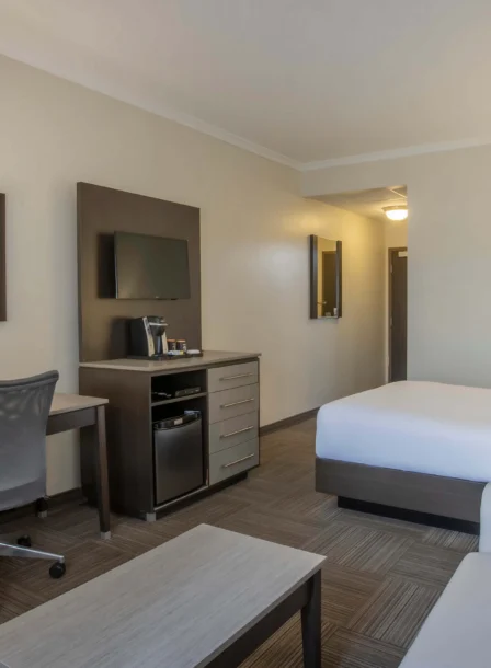 Modern hotel room with a cosy double bed, desk, and seating area for relaxation.