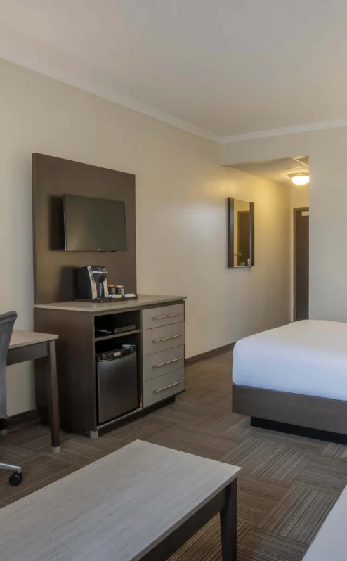Modern hotel room with a cosy double bed, desk, and seating area for relaxation.