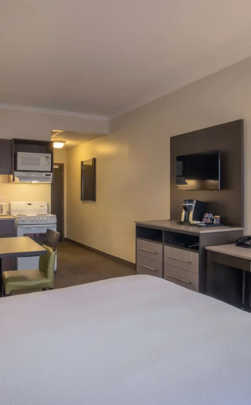 Cosy hotel suite with kitchenette, seating area, and warm lighting.