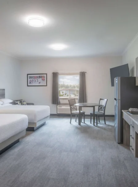 Spacious hotel room with two beds and kitchenette at Crossroads Inn & Suites.