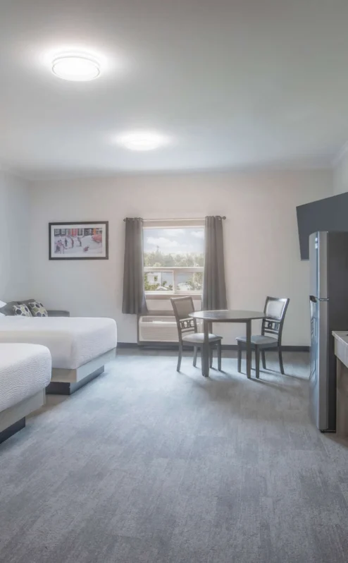 Spacious hotel room with two beds and kitchenette at Crossroads Inn & Suites.