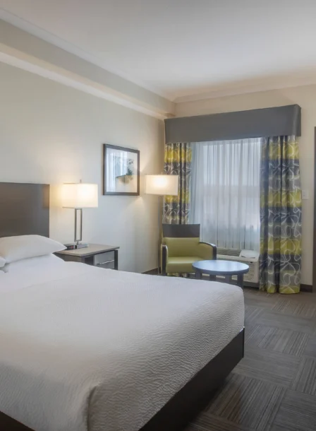 Modern hotel room with a cosy double bed, seating area, and desk in Crossroads Inn & Suites.