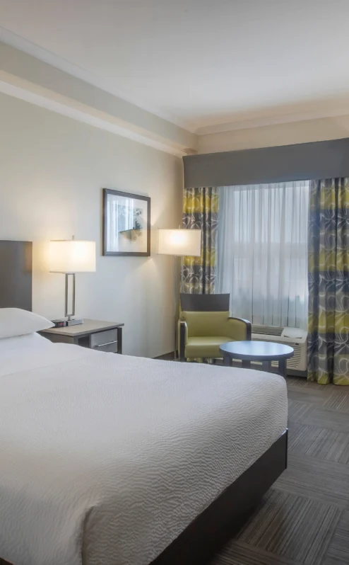 Modern hotel room with a cosy double bed, seating area, and desk in Crossroads Inn & Suites.