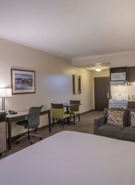 Spacious hotel room with cosy seating, kitchenette, and dining area for family relaxation.