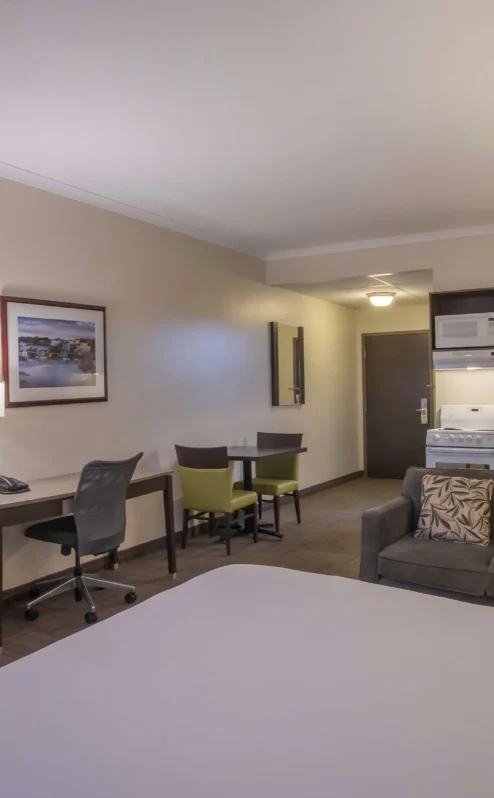 Spacious hotel room with cosy seating, kitchenette, and dining area for family relaxation.