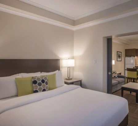 Spacious hotel suite with cosy bed, modern decor, and kitchenette for a family stay.