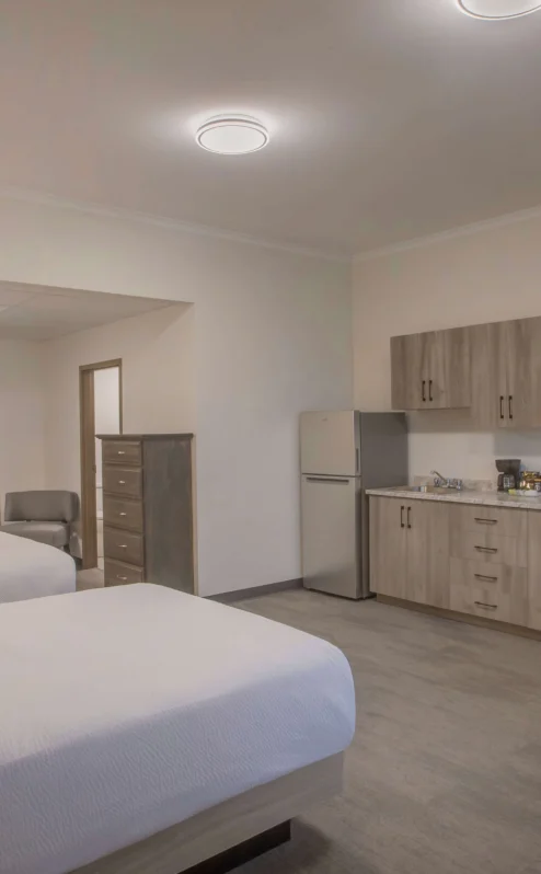 Spacious hotel room with twin beds, kitchenette, and warm lighting.