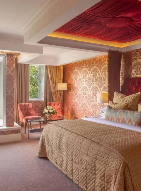 Elegant family suite with king bed, cosy seating by open window and floral welcome tray