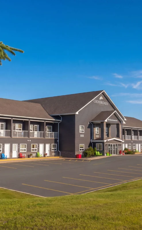 Family arriving at Crossroads Inn & Suites, set against a clear blue sky.