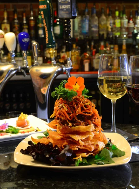 Family enjoys gourmet meal at cosy hotel bar with wine and appetisers.