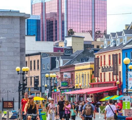 Family strolling and cycling along colourful downtown street dining and shops, lively scene (Crossroads Inn & Suites sign)