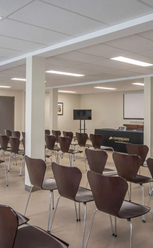 Spacious conference room setup at Crossroads Inn & Suites with chairs and presentation area.